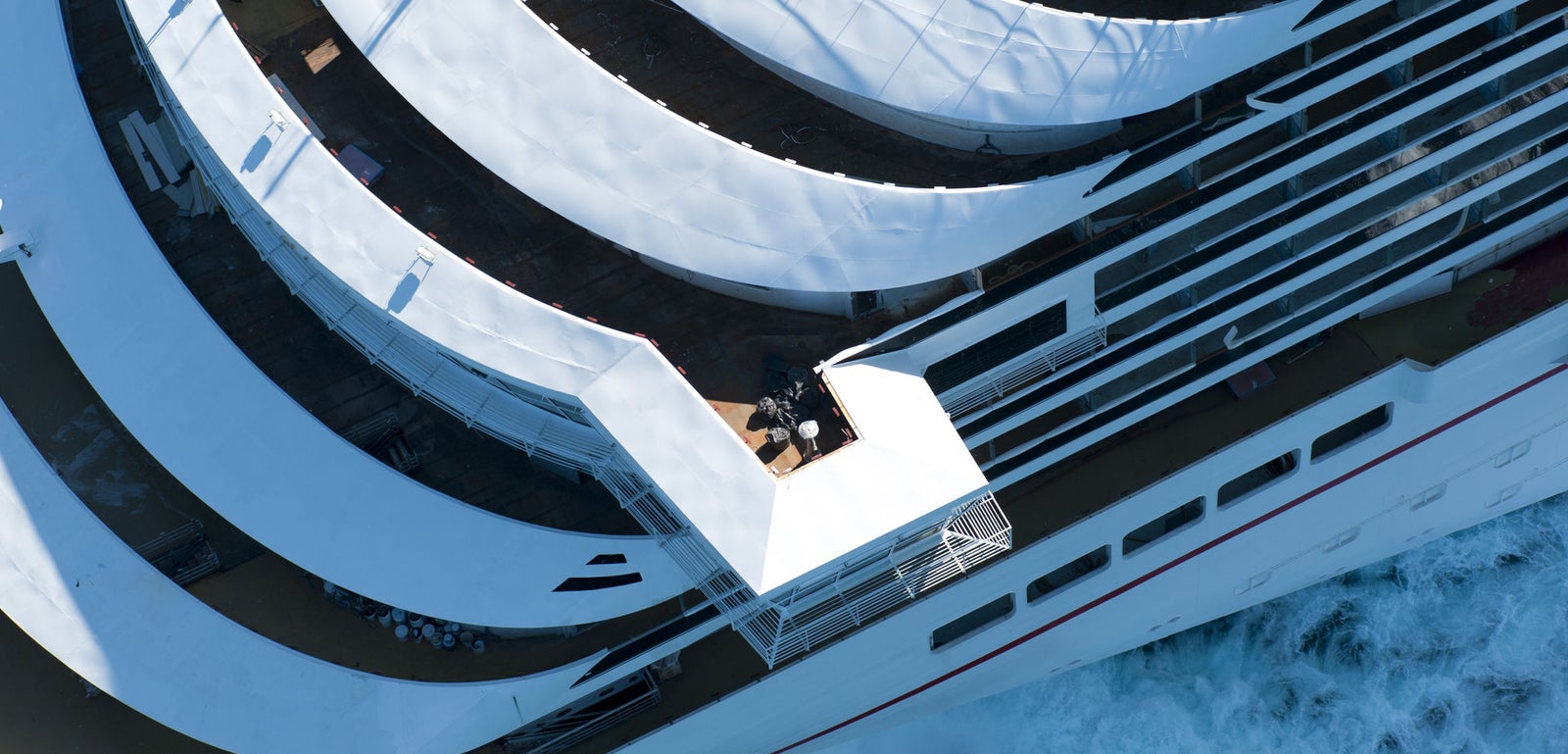 Fincantieri | Group - Business - Products - Cruise Ships - Carnival Magic: Front view of Carnival Magic cruise ship bow in operation navigating vibrant blue waters, name visible on hull, deck with seating areas and whirlpools, scene captures ship’s dynamism and serene maritime environment.
