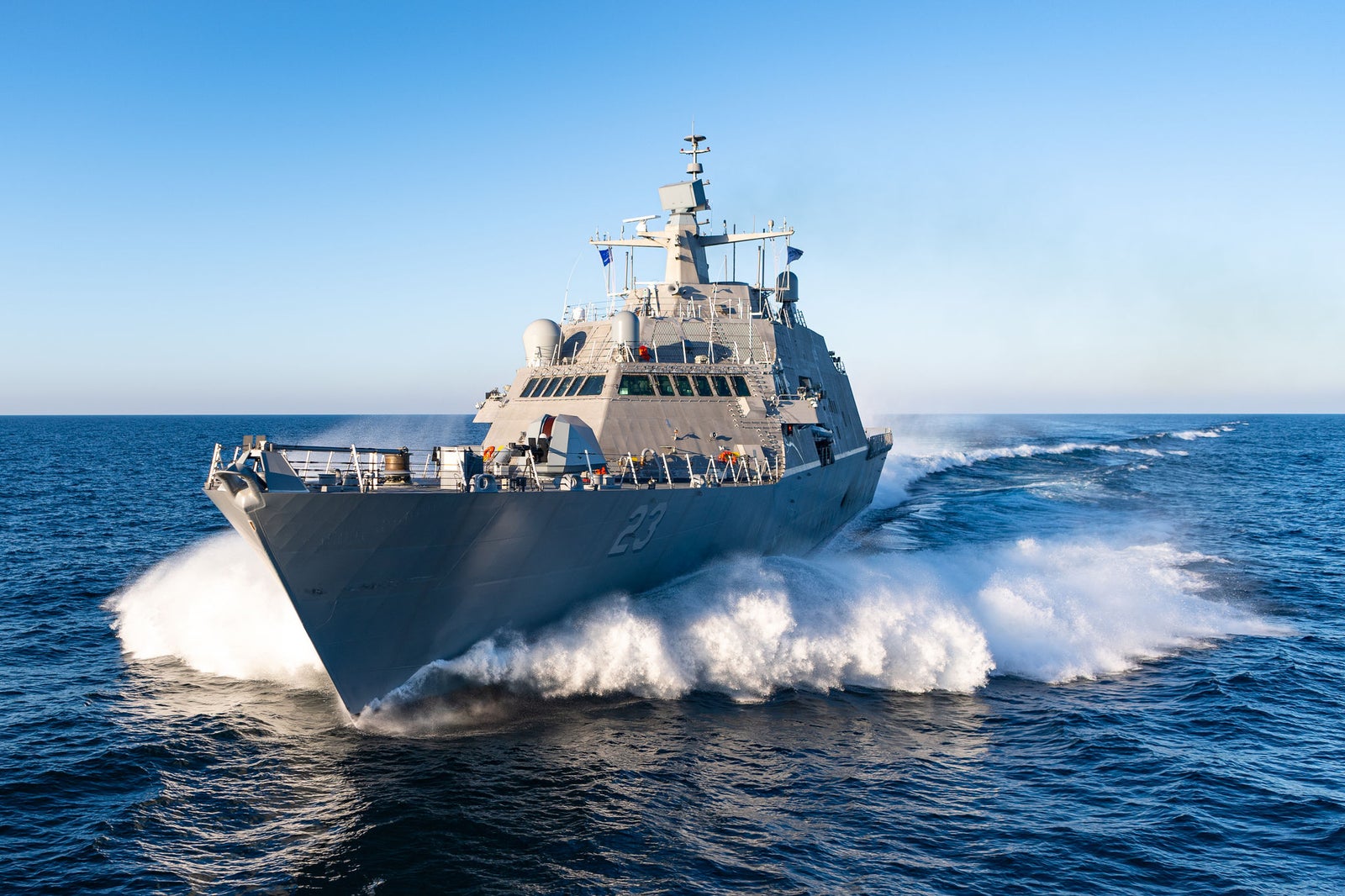  Fincantieri | Chi siamo - Eredità e Futuro: Nave militare in navigazione di fornte. La prua solca il mare sollevando ampi schizzi di spuma ai lati. Operativa