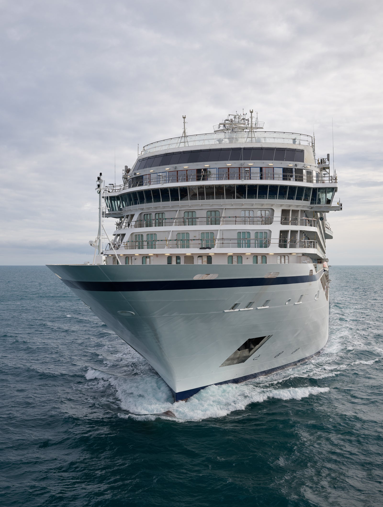 Fincantieri | Gruppo - Business - Prodotti - Navi da Crociera - Viking Mars: Vista di prua della nave Viking Mars operativa in navigazione su mare aperto, scafo bianco ben illuminato, più ponti con balconi e vetrate visibili, ampio cielo nuvoloso sopra l’orizzonte.