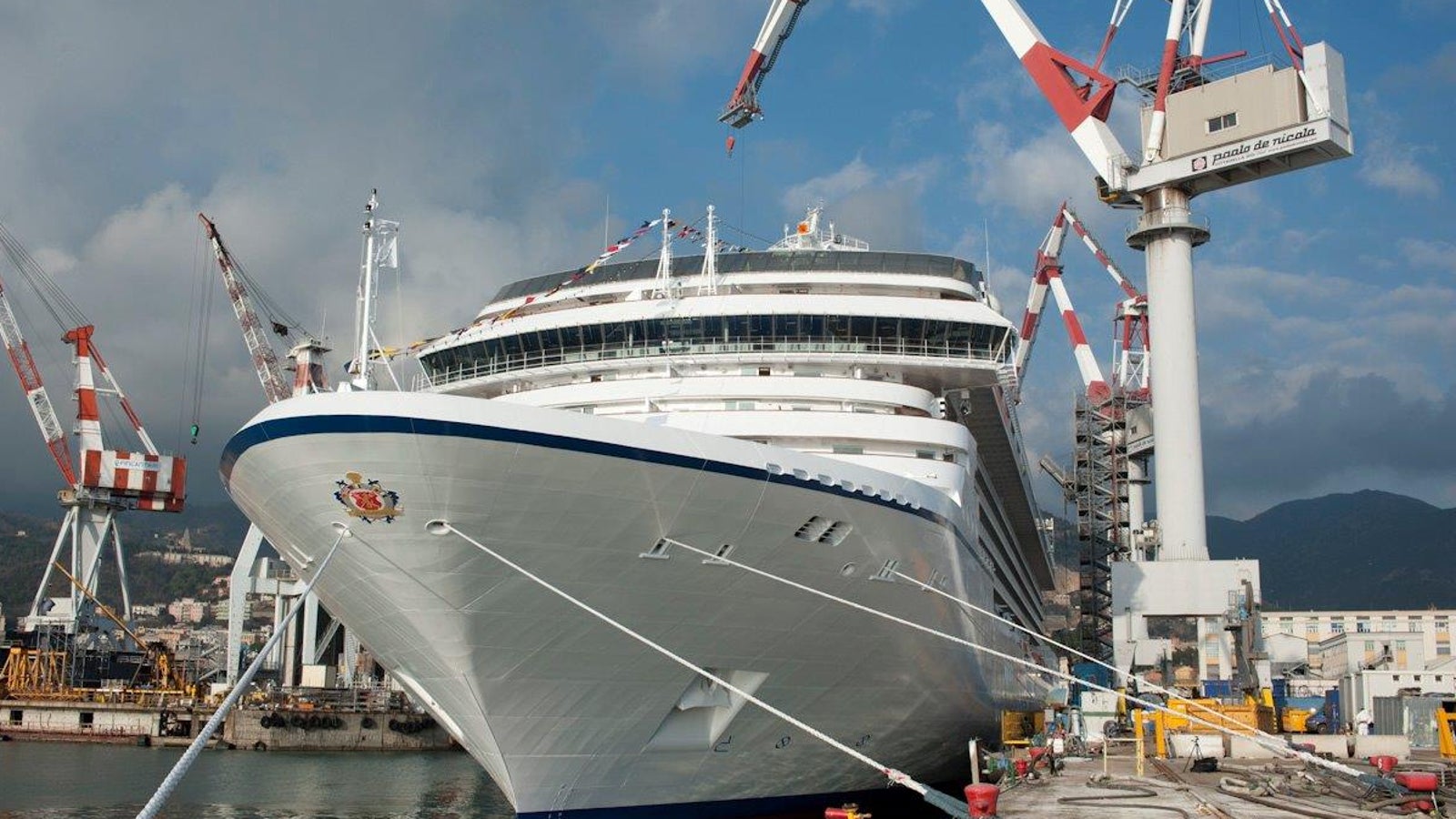 Fincantieri | Group - Business - Products - Cruise Ships - Marina: Bow view of Marina ship docked at shipyard, cranes and industrial equipment visible, Marina name and emblem on hull, construction and maintenance setting.