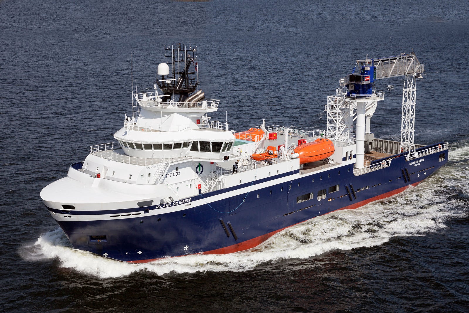 Prodotto - Offshore Support Vessel Island Diligence: Vista laterale della nave moderna in navigazione, scafo blu e sovrastruttura bianca, gru, scialuppe e numero 37 visibili, navigazione in acque tranquille con colline sullo sfondo.