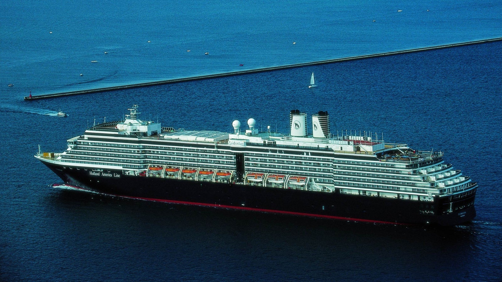 Fincantieri | Group - Business - Products - Cruise Ships - Zuiderdam: View of Zuiderdam cruise ship in operation, multiple passenger decks, visible lifeboats and funnels, surrounded by smaller vessels.