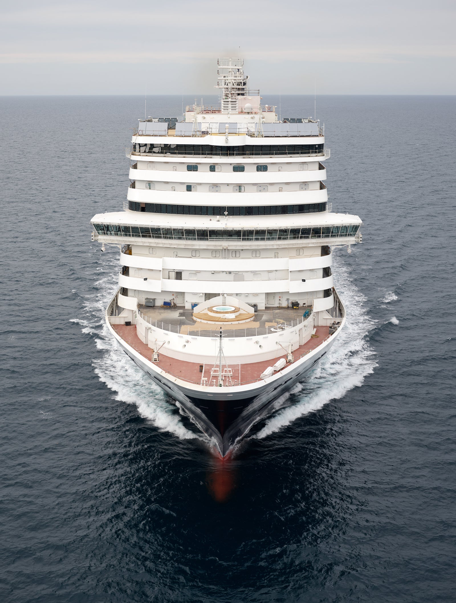 Fincantieri | Group - Business - Products - Cruise Ships - Rotterdam: Front view of large multi-deck cruise ship in operation, sailing on calm open waters under cloudy sky, elegant design with outdoor decks and visible seating areas.