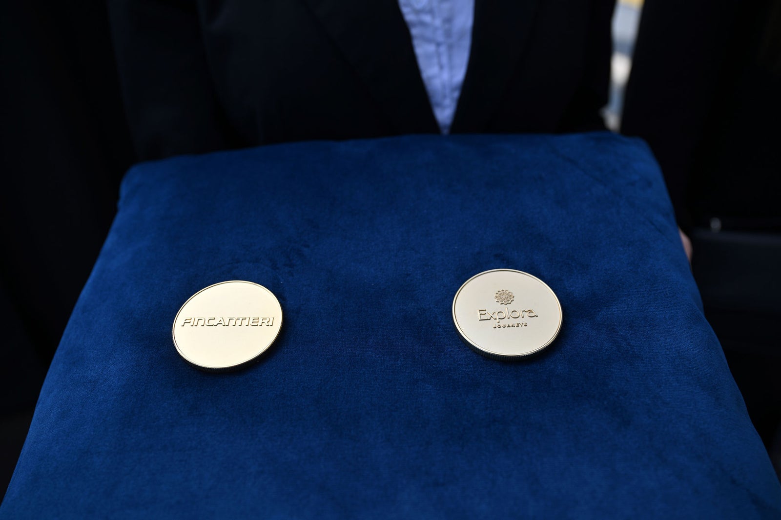 Newsroom - Press releases - 2026 - Fincantieri Group: Fincantieri:  Today triple ceremony for Fincantieri and Explora Journeys at Sestri Ponente: launche of Explora IV, coin ceremony for Explora V and steel cuttingfor Explora VI: Two commemorative coins with Fincantieri and Explora Journeys logos displayed on a blue velvet cushion.