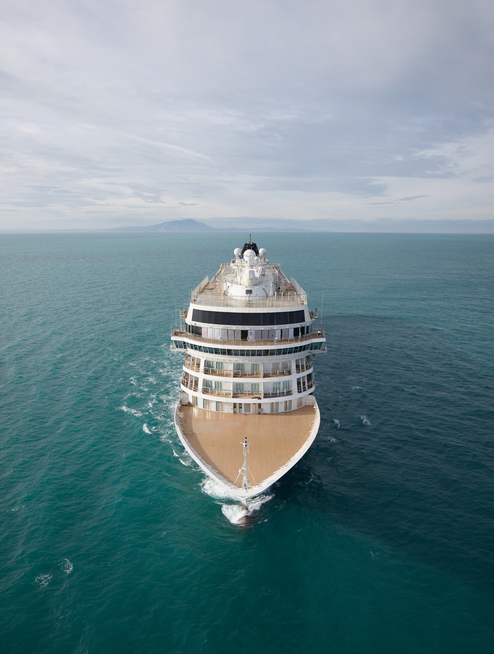  Fincantieri | Group - Business - Products - Cruise Ships - Viking Saturn: Large luxury cruise ship in operation, sailing in open sea under cloudy sky, visible deck and multiple levels, calm ocean and distant horizon, serene expansive setting.