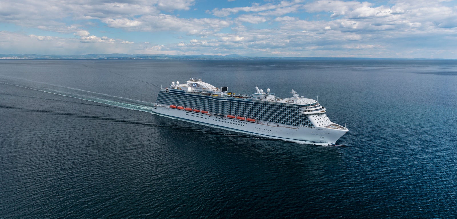 Fincantieri | Group - Business - Products - Cruise Ships - Regal Princess: Large operational cruise ship gliding on calm open waters under partly cloudy sky, serene ocean environment with no land visible nearby.