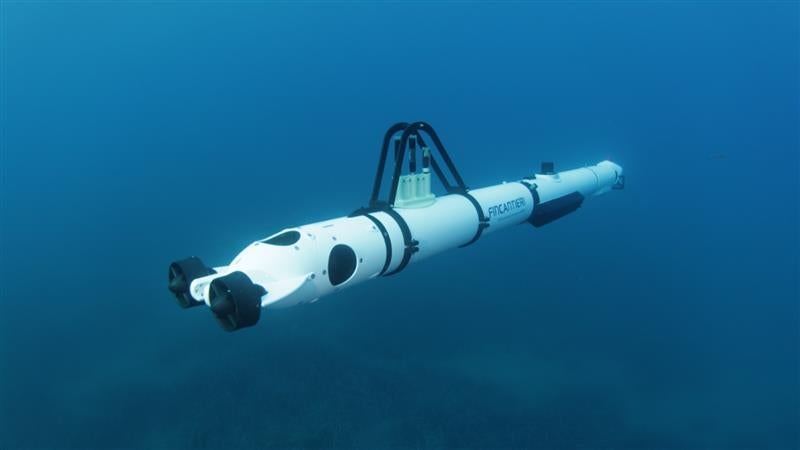 Fincantieri | Newsroom, Deep: A sleek white underwater autonomous vehicle is shown submerged in a deep ocean setting. The vehicle features a streamlined design with visible sensors and equipment mounted on its body. The text 'Hydroid' is clearly visible on the side, indicating the model or brand. The image captures a serene underwater environment with a blue palette.