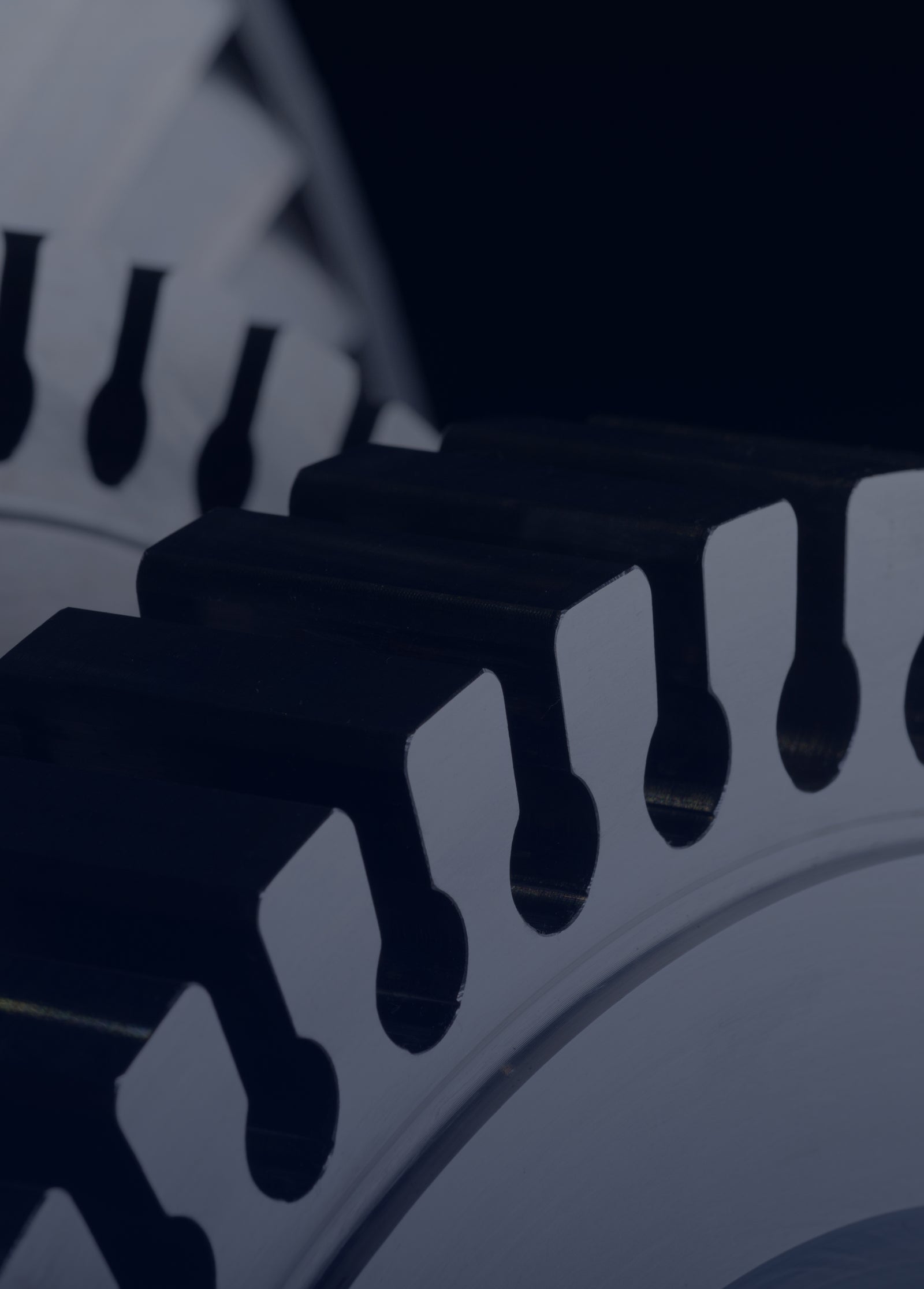 Fincantieri | Group - Governance and Ethics - Corporate Governance System: Close-up of interlocked metallic gears on a dark background, with focus on the teeth and metal texture.