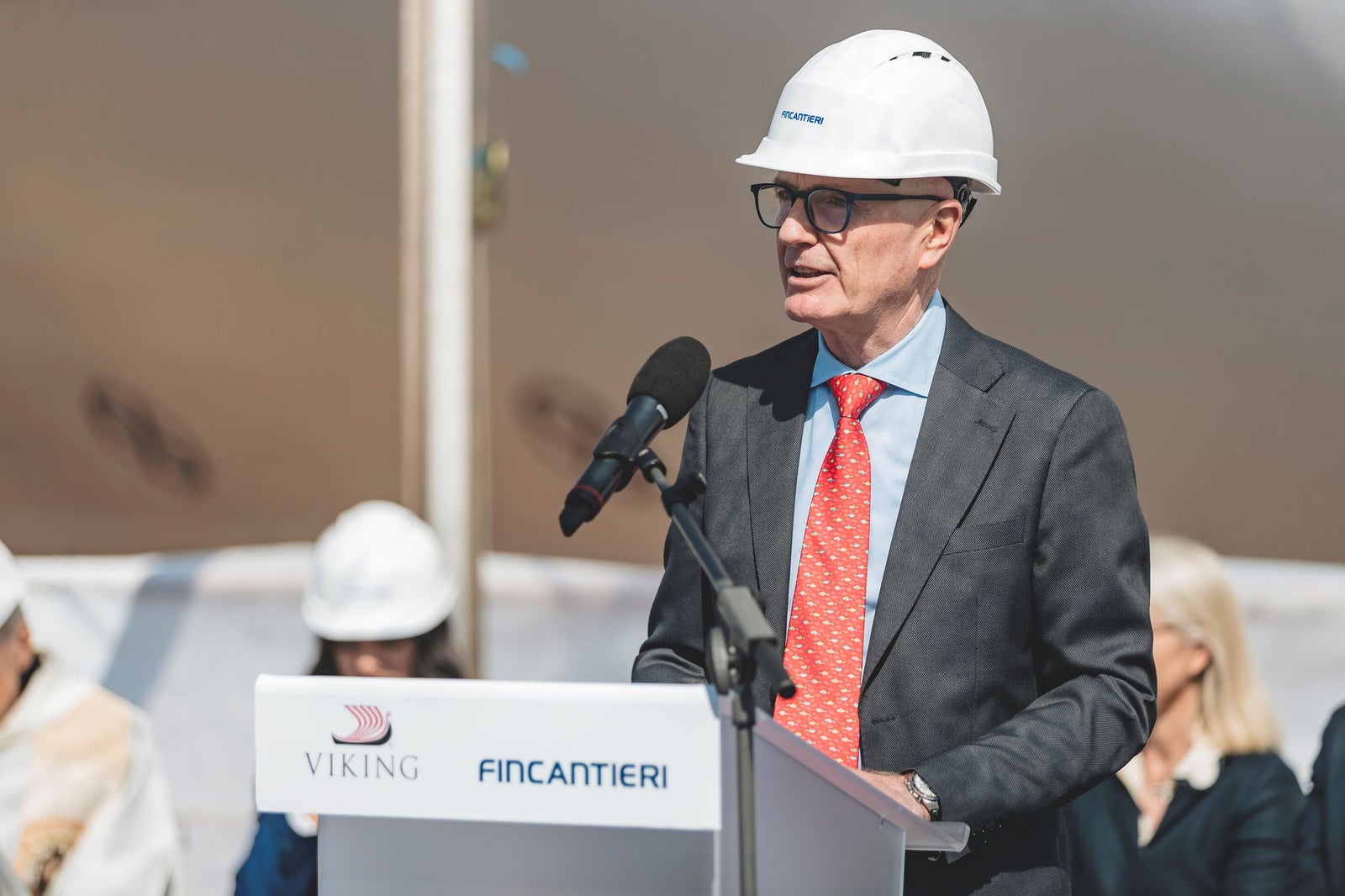 Newsroom - Press releases - 2026 - Fincantieri Group: Fincantieri: “Viking Libra” launched in Ancona, the world’s first hydrogen-powered cruise ship: Fincantieri executive with helmet and red tie speaks at podium with Viking and Fincantieri logos during launch event.