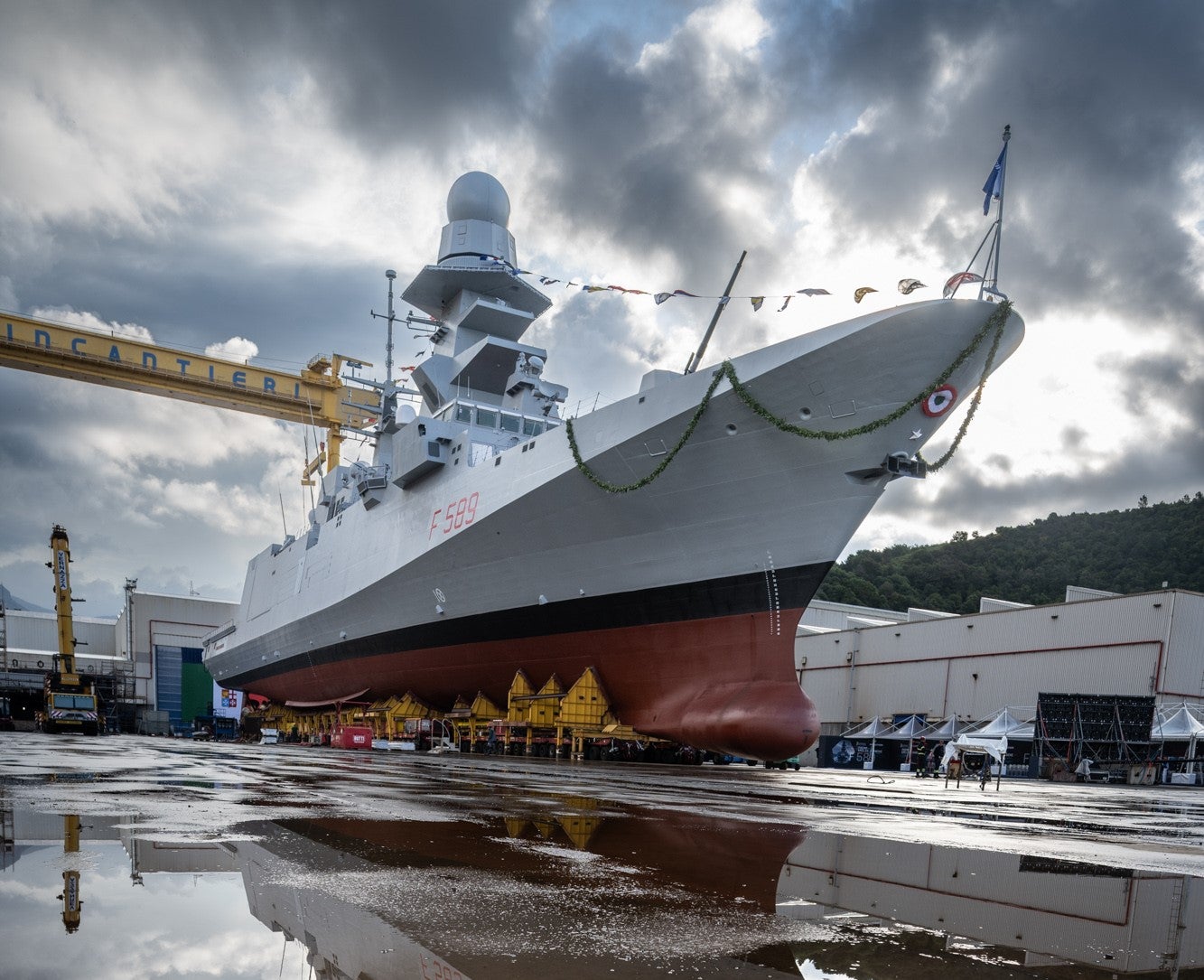  Newsroom - Comunicati stampa - 2025 - Gruppo Fincantieri: Difesa: consegnata alla Marina Militare la decima Unità Fremm "Emilio Bianchi": La fregata FREMM "Emilio Bianchi" in cantiere durante la cerimonia di consegna, vista della prua decorata, infrastrutture industriali e dettagli navali ben visibili.