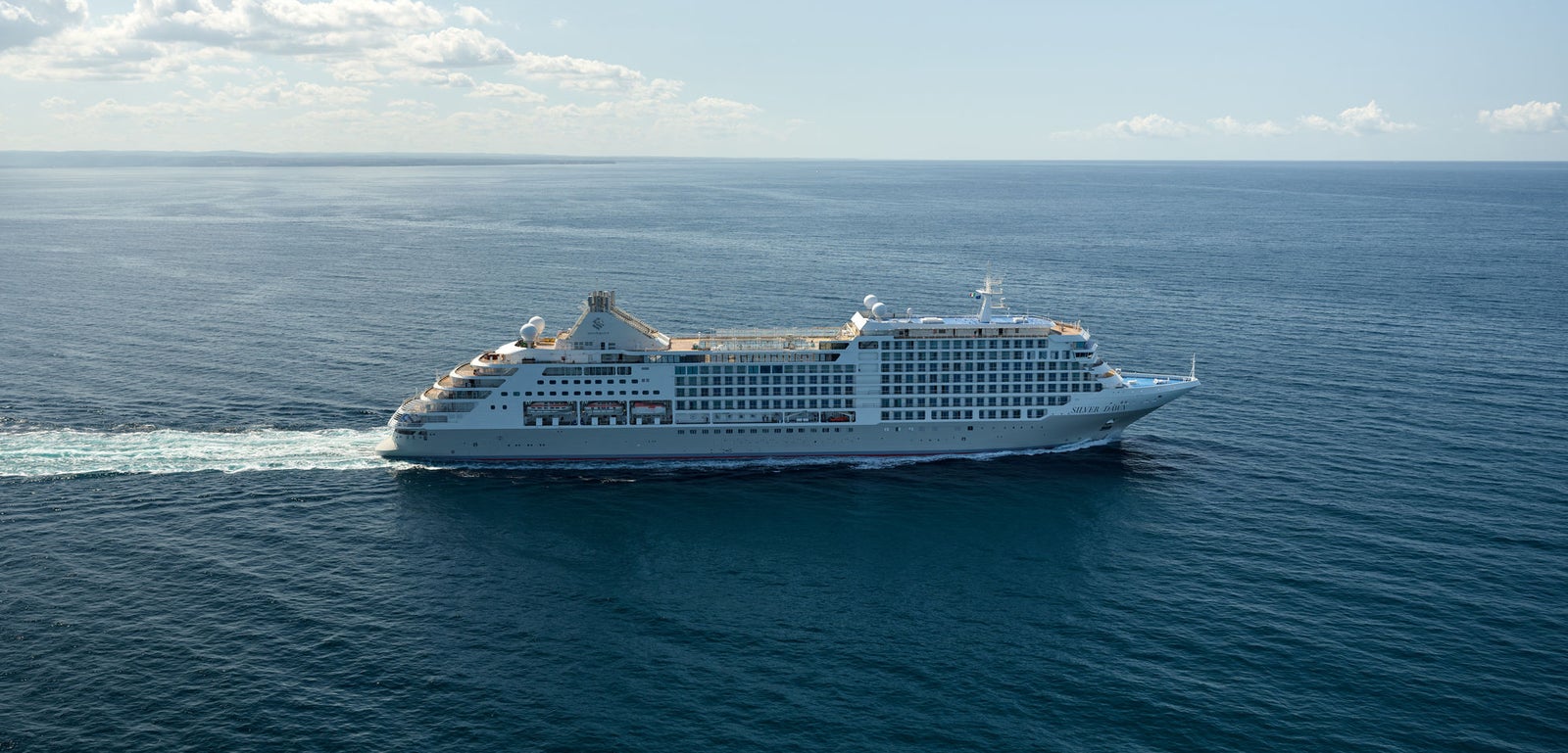  Fincantieri | Group - Business - Products - Cruise Ships - Silver Dawn: White cruise ship in operation gliding across calm deep blue ocean under clear sky, multiple decks and visible windows, setting highlights sea vastness and tranquility of journey.