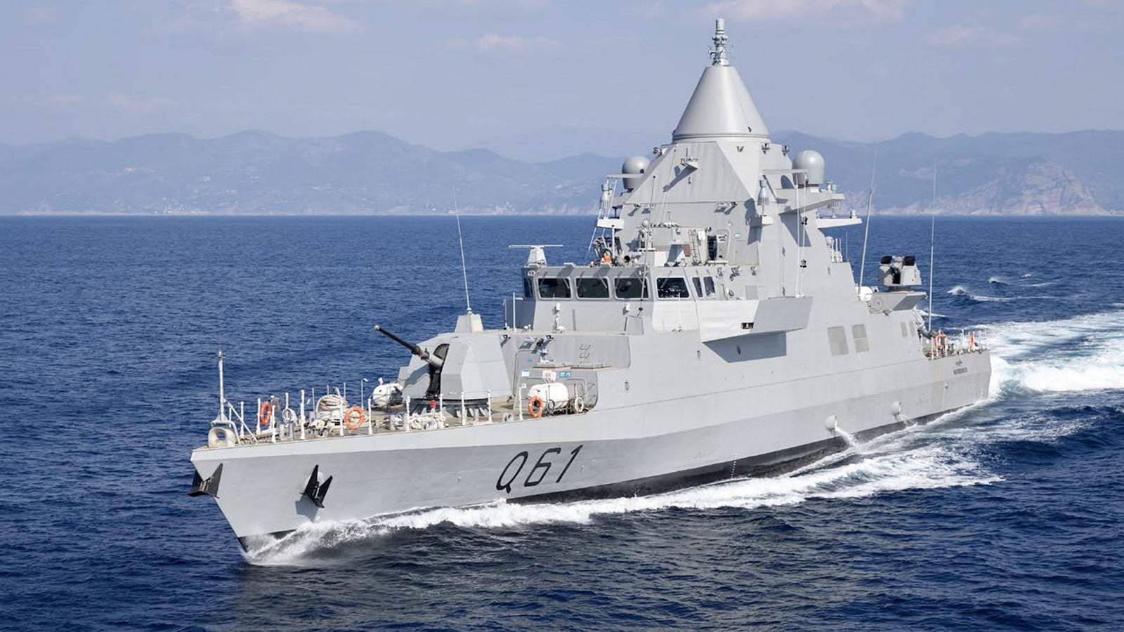 Fincantieri | Group - Business - Products - Defence Vessels - Fast Attack Craft - Musherib class: Side view of operational ship underway, sleek modern design, advanced radar and armaments visible on deck, prominent white wake.