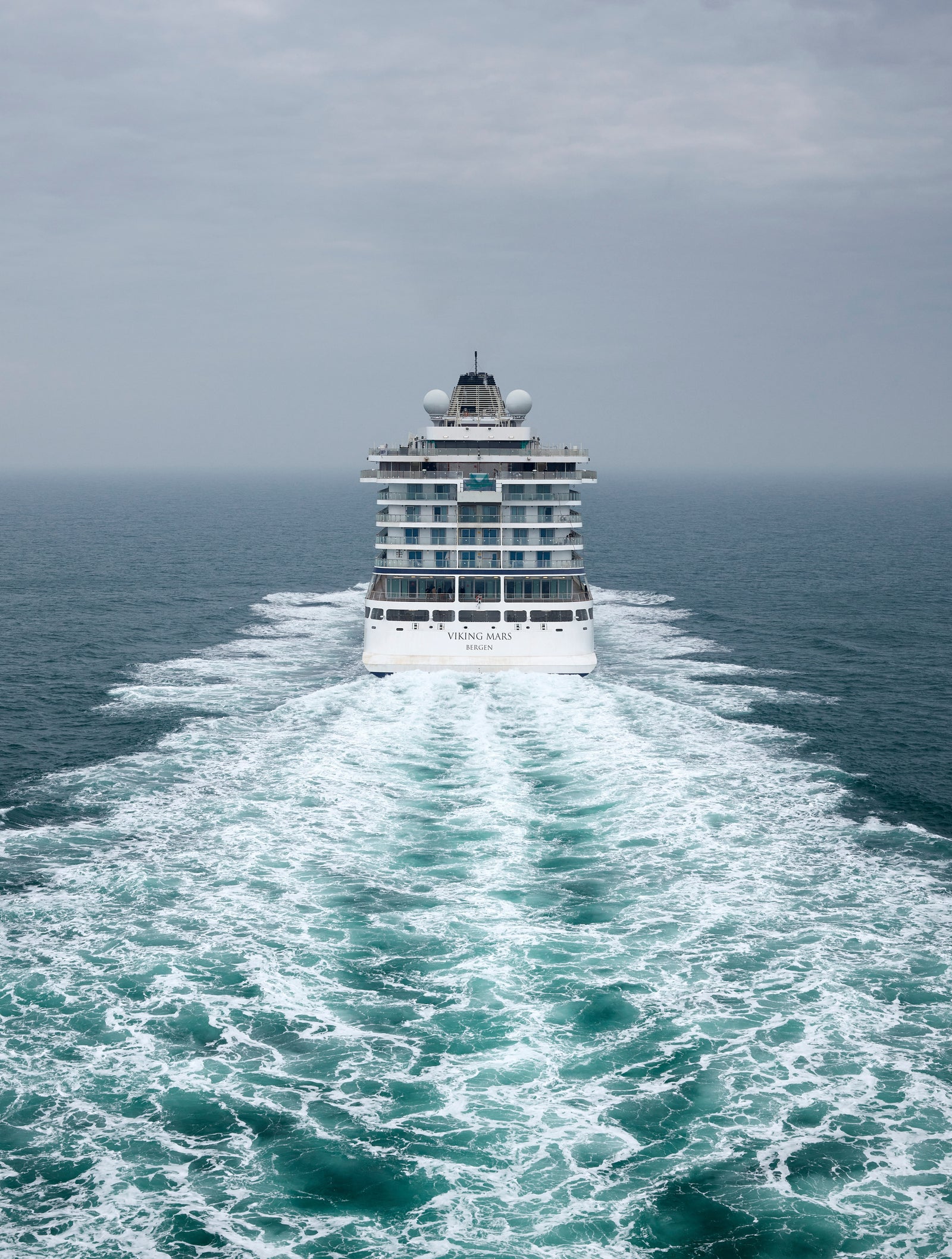  Fincantieri | Group - Business - Products - Cruise Ships - Viking Mars: Massive cruise ship in operation, navigating open ocean, visible trail of white waves behind, cloudy overcast sky, modern design with multiple decks, setting emphasizes sea vastness and ship’s grandeur.