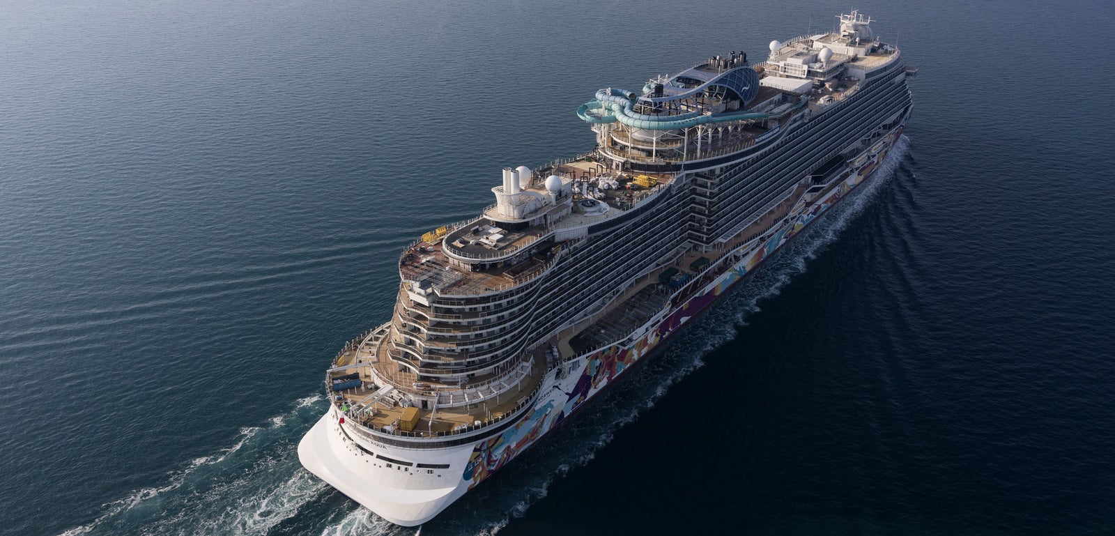Fincantieri | Group - Business - Products - Cruise Ships - Norwegian Aqua: Luxury cruise ship in operation, multiple decks, intricate design details, large outdoor recreation areas, hull decorated with colorful artwork creating a distinctive and vibrant appearance.