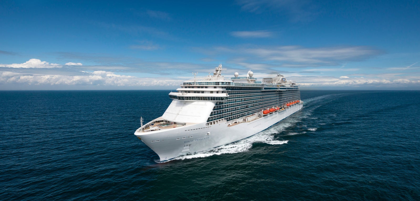 Fincantieri | Group - Business - Products - Cruise Ships - Royal Princess: Modern white cruise ship in operation sailing on calm blue waters under partly cloudy sky, multiple decks and visible lifeboats along side.