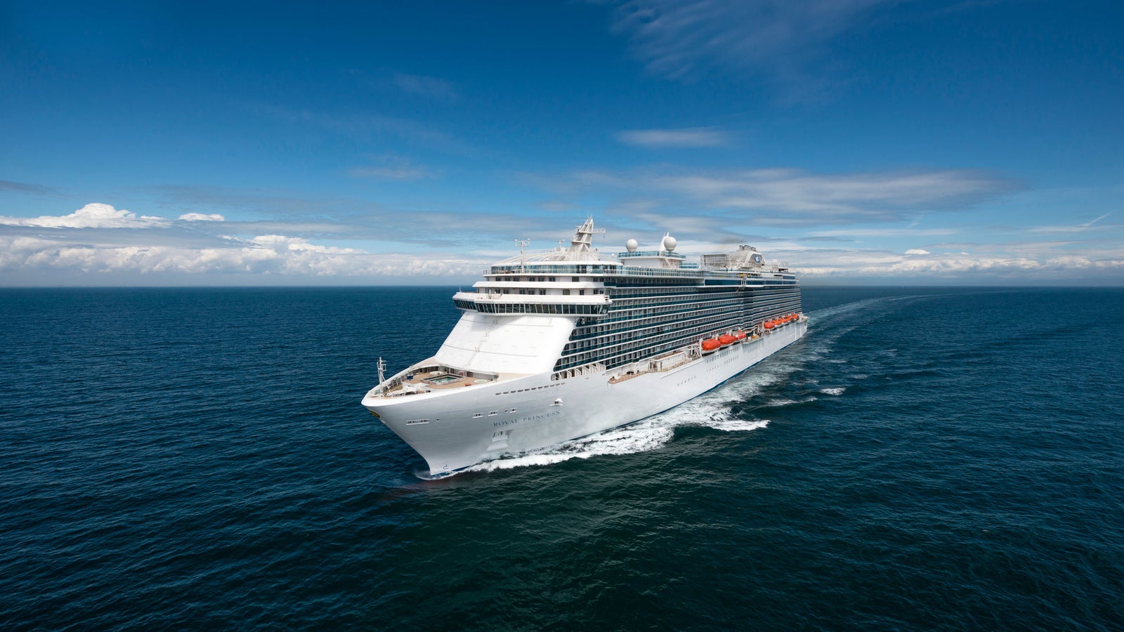 Fincantieri | Group - Business - Products - Cruise Ships - Royal Princess: Modern white cruise ship in operation sailing on calm blue waters under partly cloudy sky, multiple decks and visible lifeboats along side.