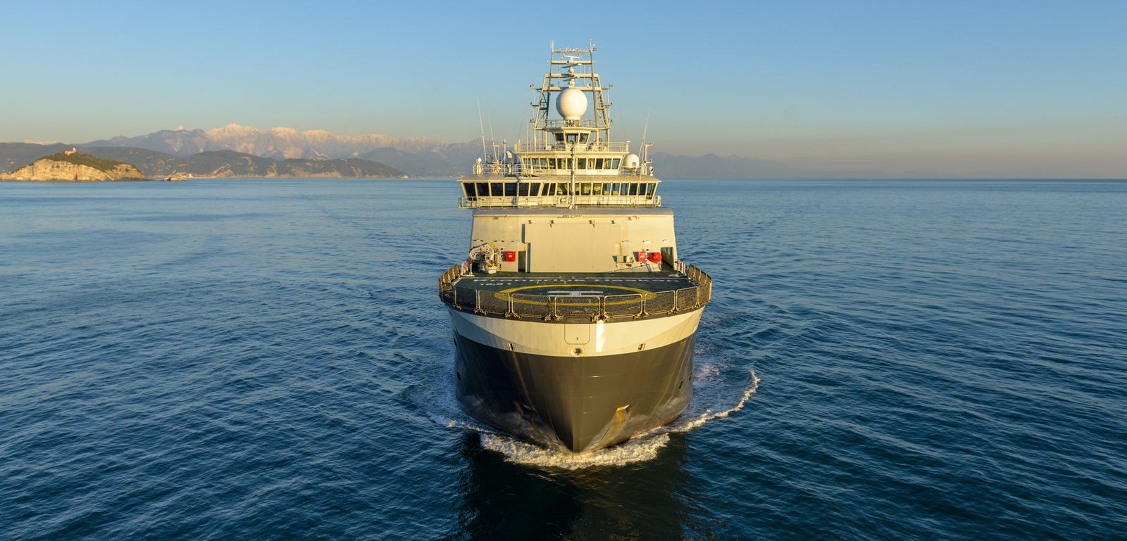 Prodotto - Nave da Ricerca Polare: Vista frontale della nave operativa in navigazione, prua rivolta verso l’osservatore, struttura ben visibile, sfondo montuoso costiero.