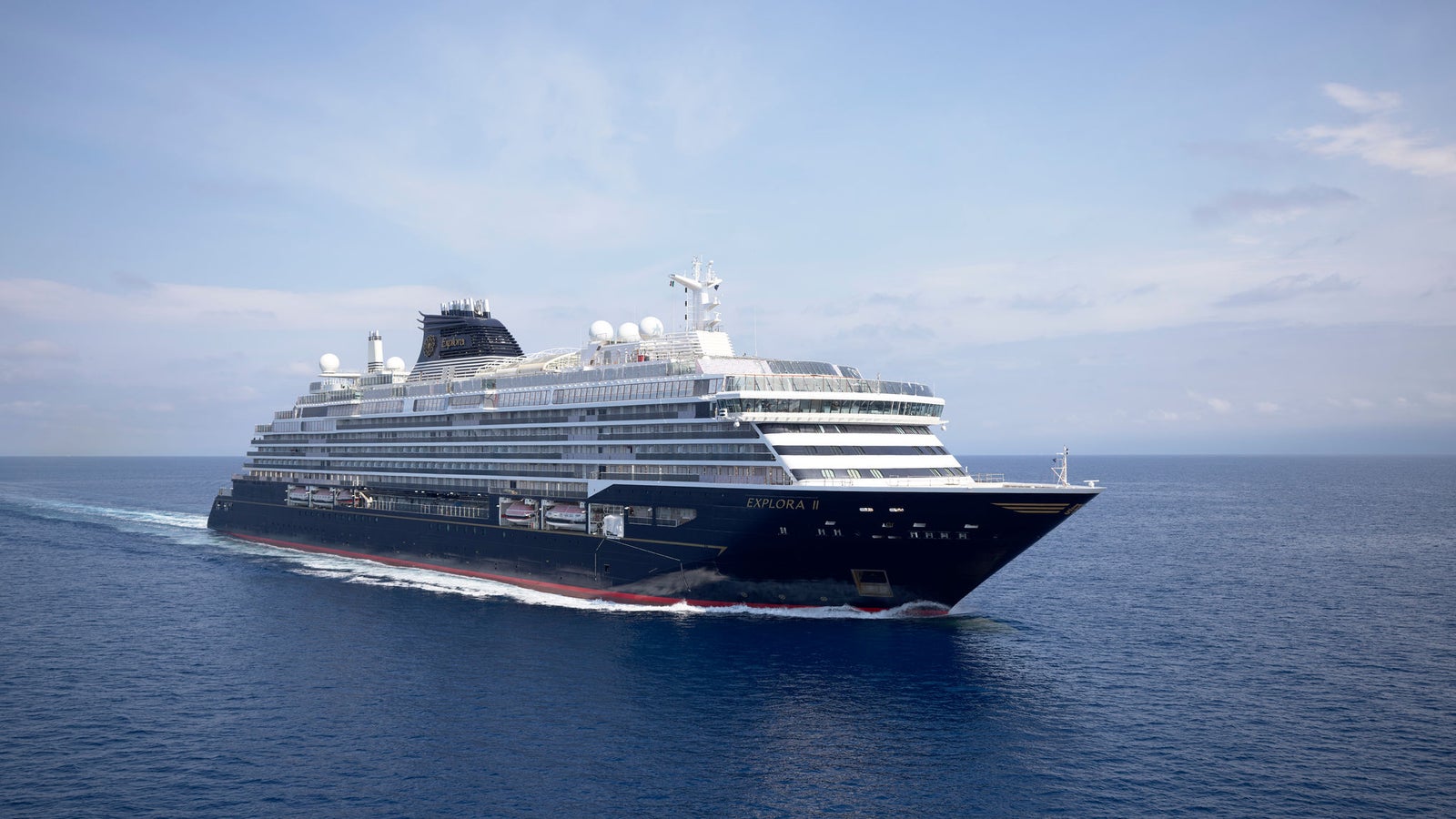 Fincantieri | Group - Business - Products - Cruise Ships - Evrima: Side view of operational cruise ship in navigation, sleek black and white design, decks and antennas visible, name Evrima clearly visible on hull.