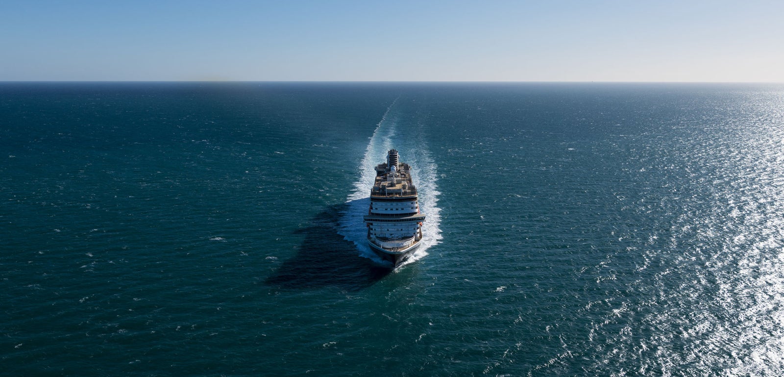 Fincantieri | Gruppo - Business - Prodotti - Navi da Crociera - Koningsdam: Vista frontale di grande nave da crociera operativa che naviga su acque calme e aperte sotto cielo azzurro limpido, struttura a più ponti e design elegante evidenziati.