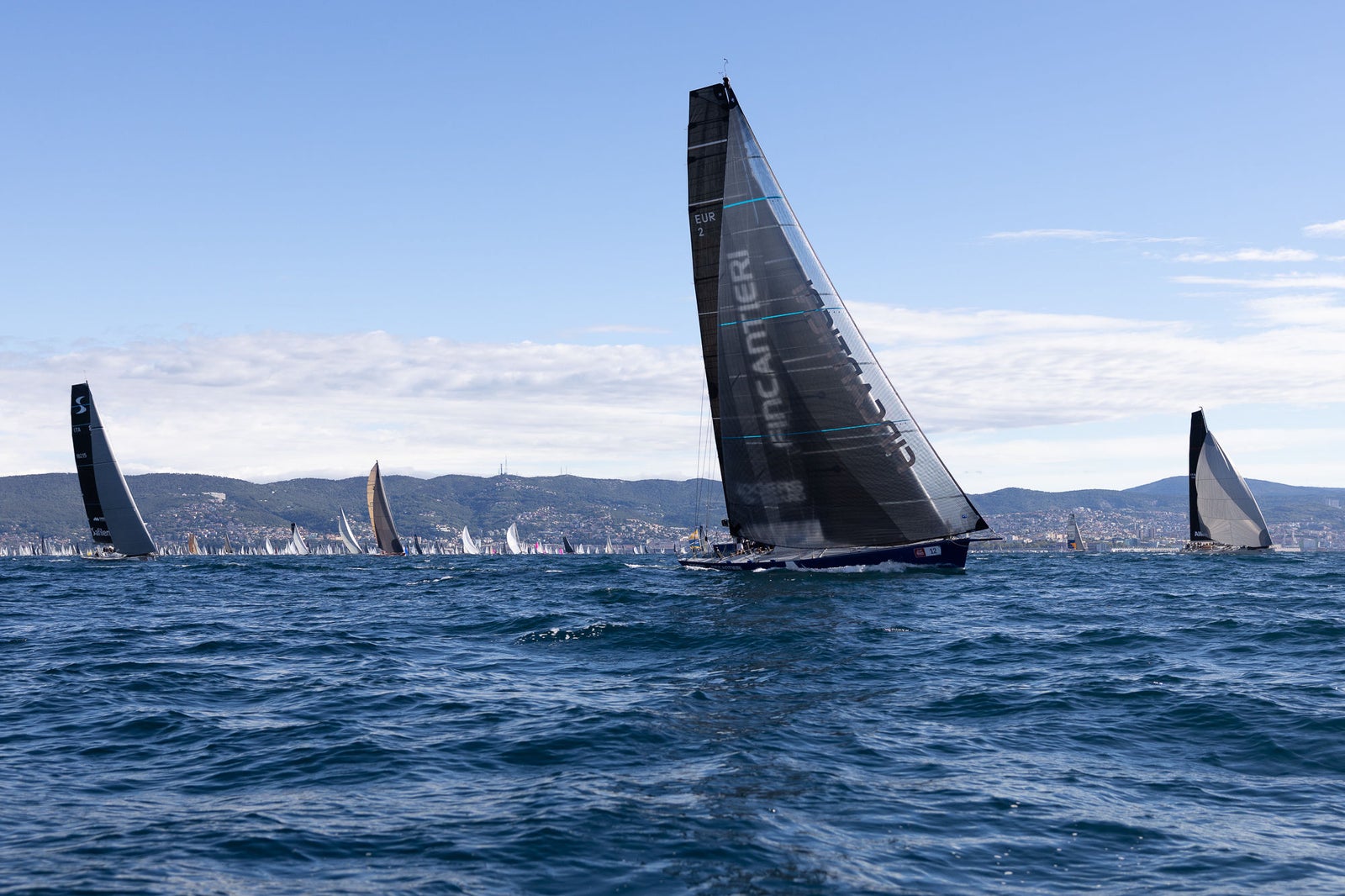 Racing sailboats on open blue sea
