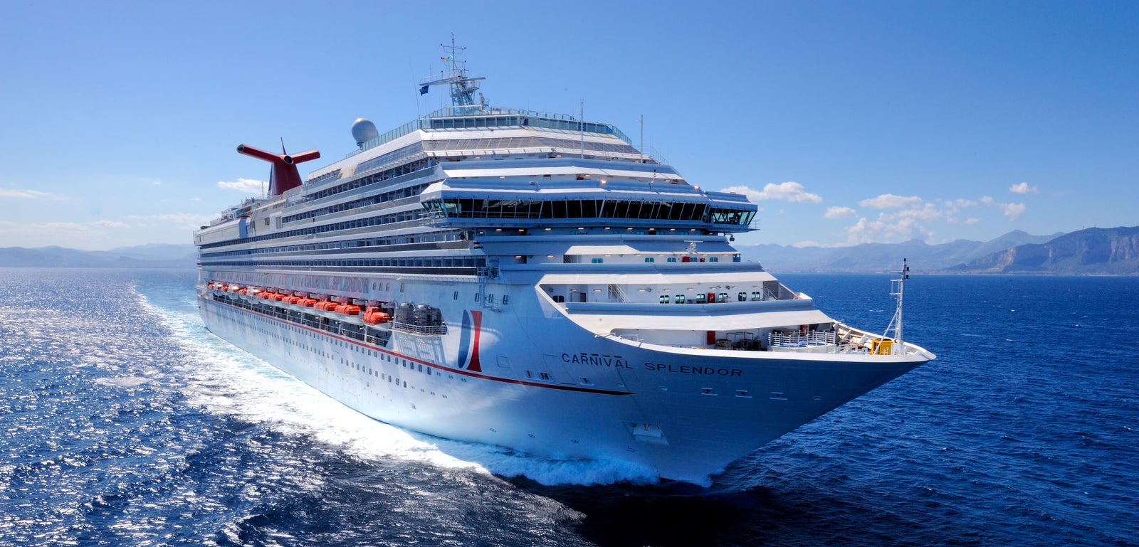 Fincantieri | Group - Business - Products - Cruise Ships - Carnival Splendor: Overhead and bow view of Carnival Splendor cruise ship in operation sailing on clear blue waters under sunny sky, multiple decks, vibrant red accents, visible identifying name text.