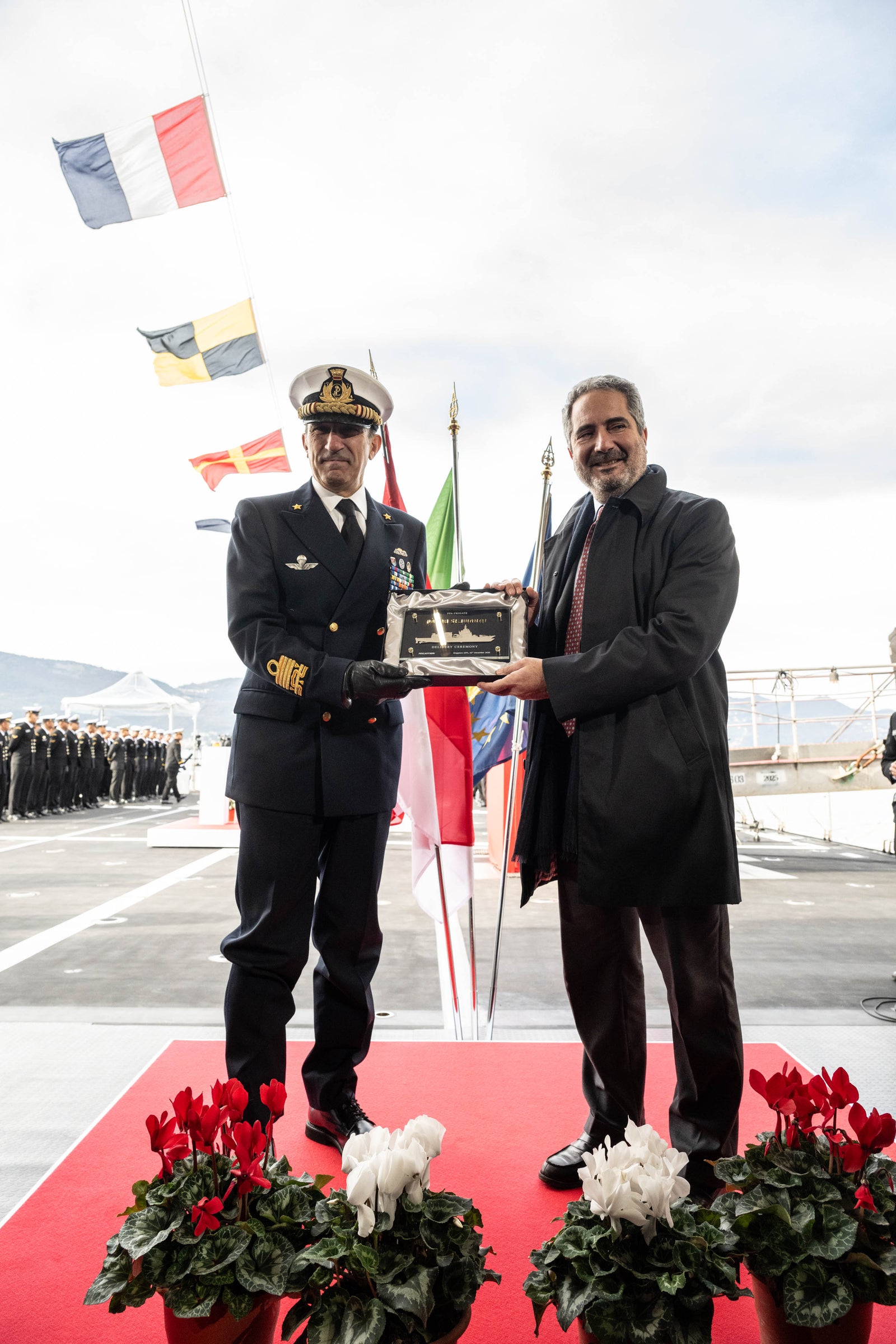 newsroom - press releases - 2025 - fincantieri group: fincantieri delivers the ppa "kri prabu siliwangi-321" to the indonesian navy: indonesian navy officer in uniform and representative holding the commemorative plaque during the official handover ceremony, national and international flags in the background.