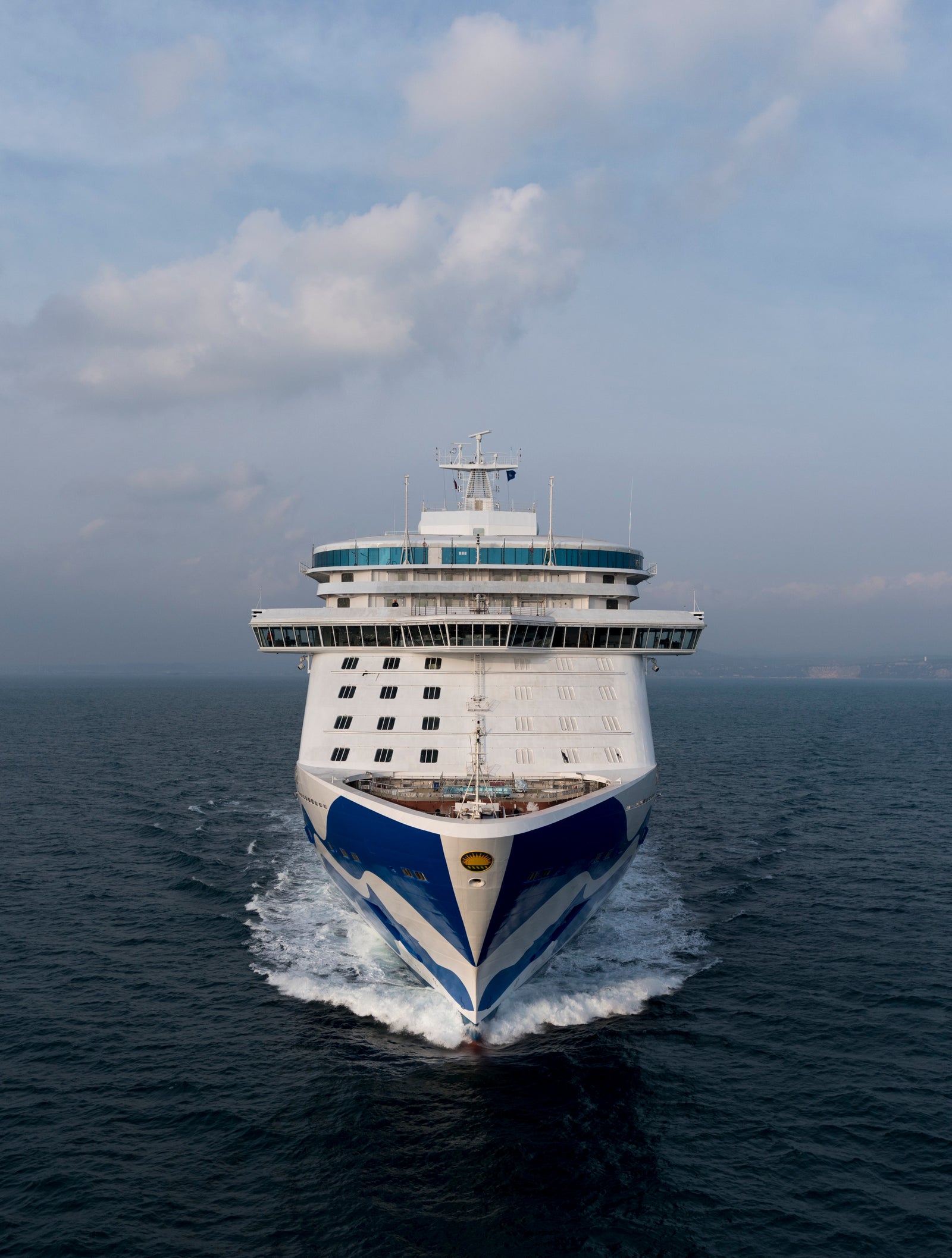 Fincantieri | Group - Business - Products - Cruise Ships - Majestic Princess: Bow view of Majestic Princess cruise ship in operation, large cruise ship with distinctive blue and white design, sailing on calm ocean waters, modern structure and grandeur emphasized.