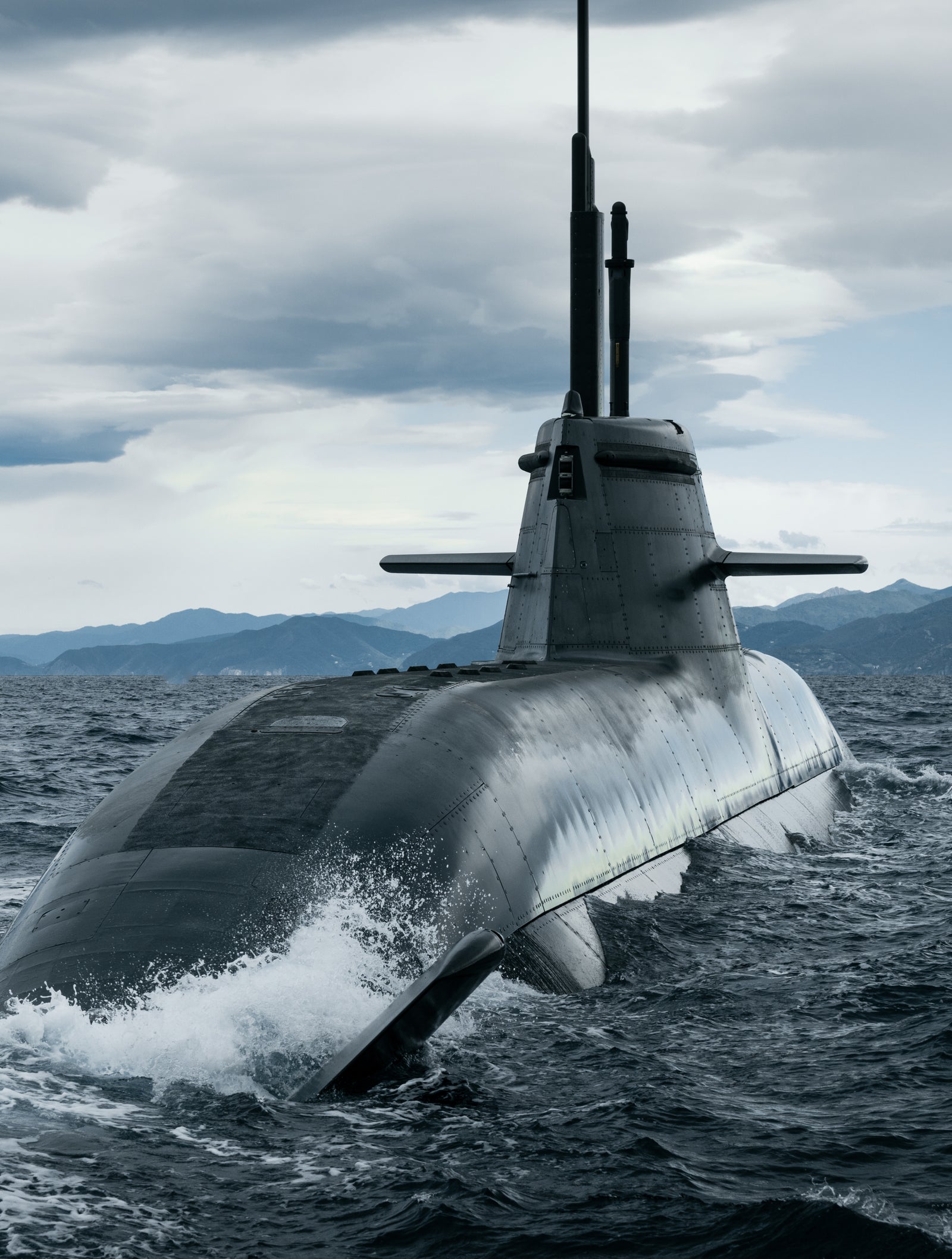 Fincantieri | Gruppo - Business - Prodotti - Sommergibili - Classe Todaro: Sommergibile militare slanciato operativo, in emersione dall’oceano, scafo che taglia le onde, cielo nuvoloso, acque ampie, montagne lontane sull’orizzonte, design stealth e potente.