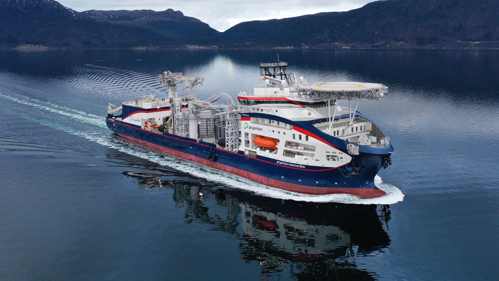 Prodotto - Nave Monna Lisa: Vista laterale della nave operativa in navigazione tra rilievi montuosi, scafo rosso, bianco e blu, equipaggiamenti di coperta visibili, design moderno.