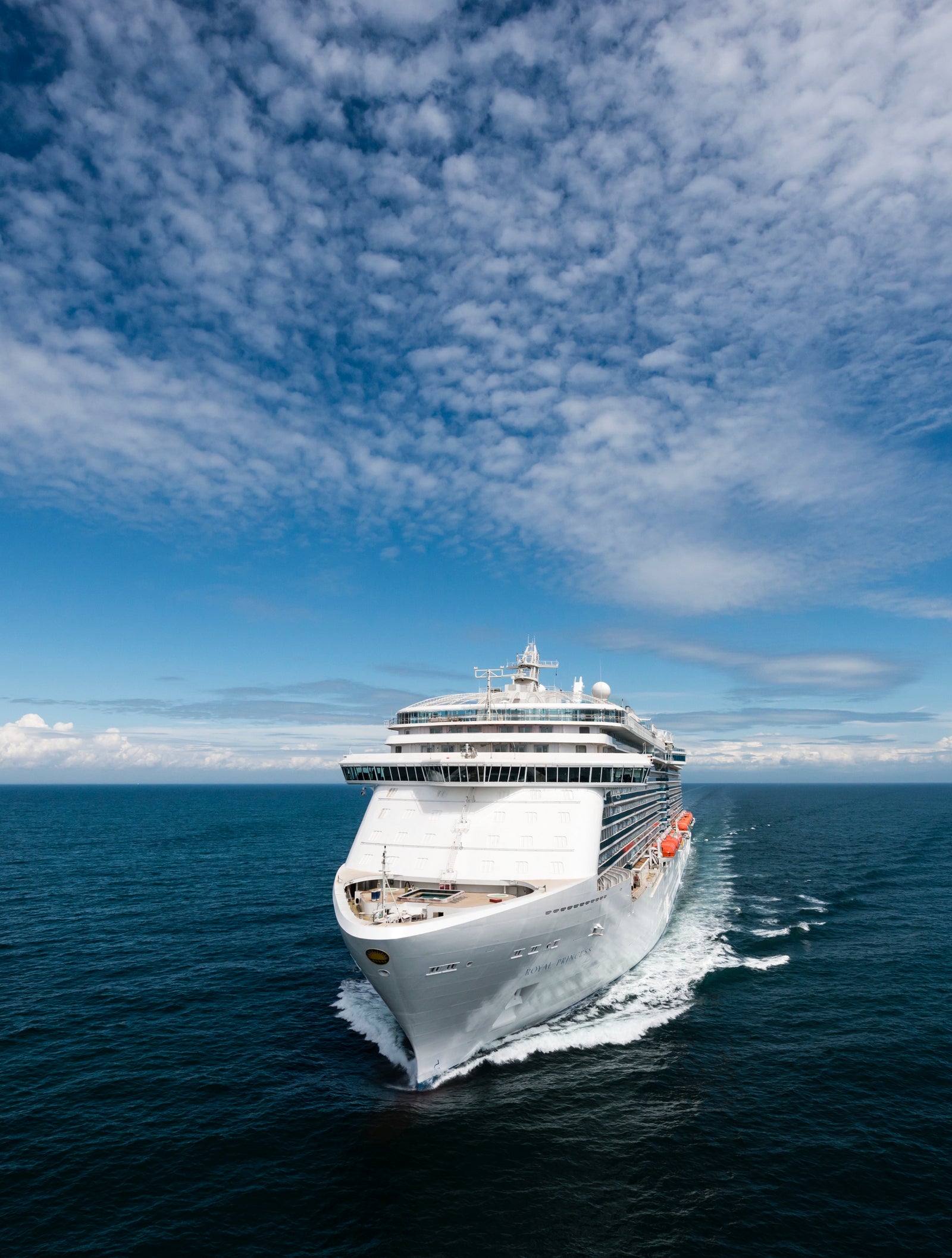 Fincantieri | Group - Business - Products - Cruise Ships - Royal Princess: Modern white cruise ship in operation sailing on calm blue waters under partly cloudy sky, multiple decks and visible lifeboats along side.