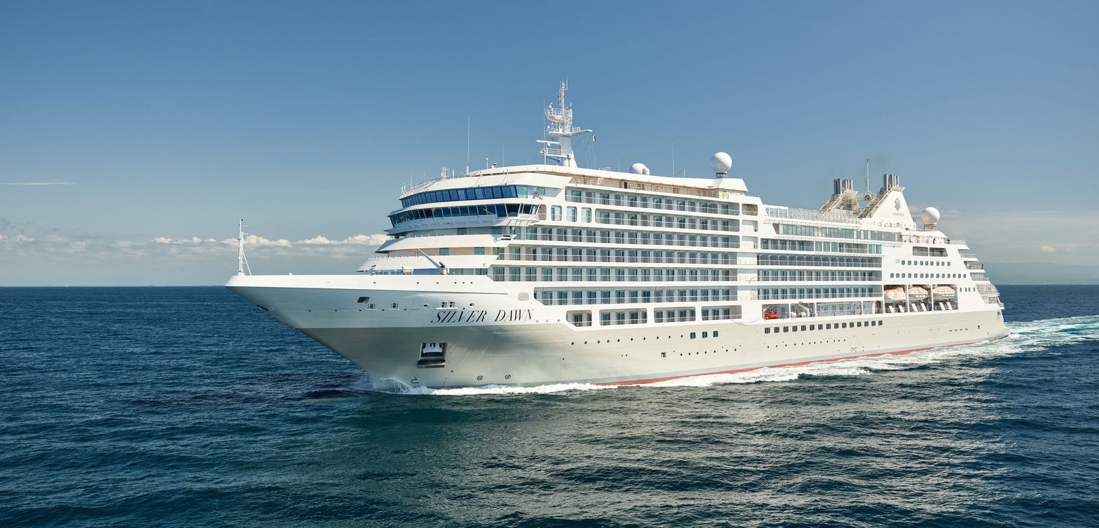  Fincantieri | Group - Business - Products - Cruise Ships - Silver Dawn: Silver Dawn cruise ship in operation sailing through calm ocean waters under clear blue sky, name prominently visible on hull, elegant design with multiple decks, scene captures modern maritime grandeur and serene open sea.