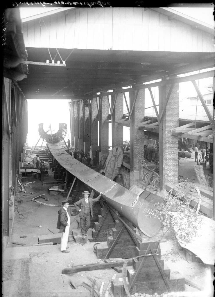 newsroom - press releases - 2026 - fincantieri group - fincantieri foundation: the first volume of the series on the history of italian shipbuilding now available in bookstores: fotografia storica in bianco e nero di officina navale con operai e costruzione struttura cilindrica di sommergibile tra pilastri in mattoni.