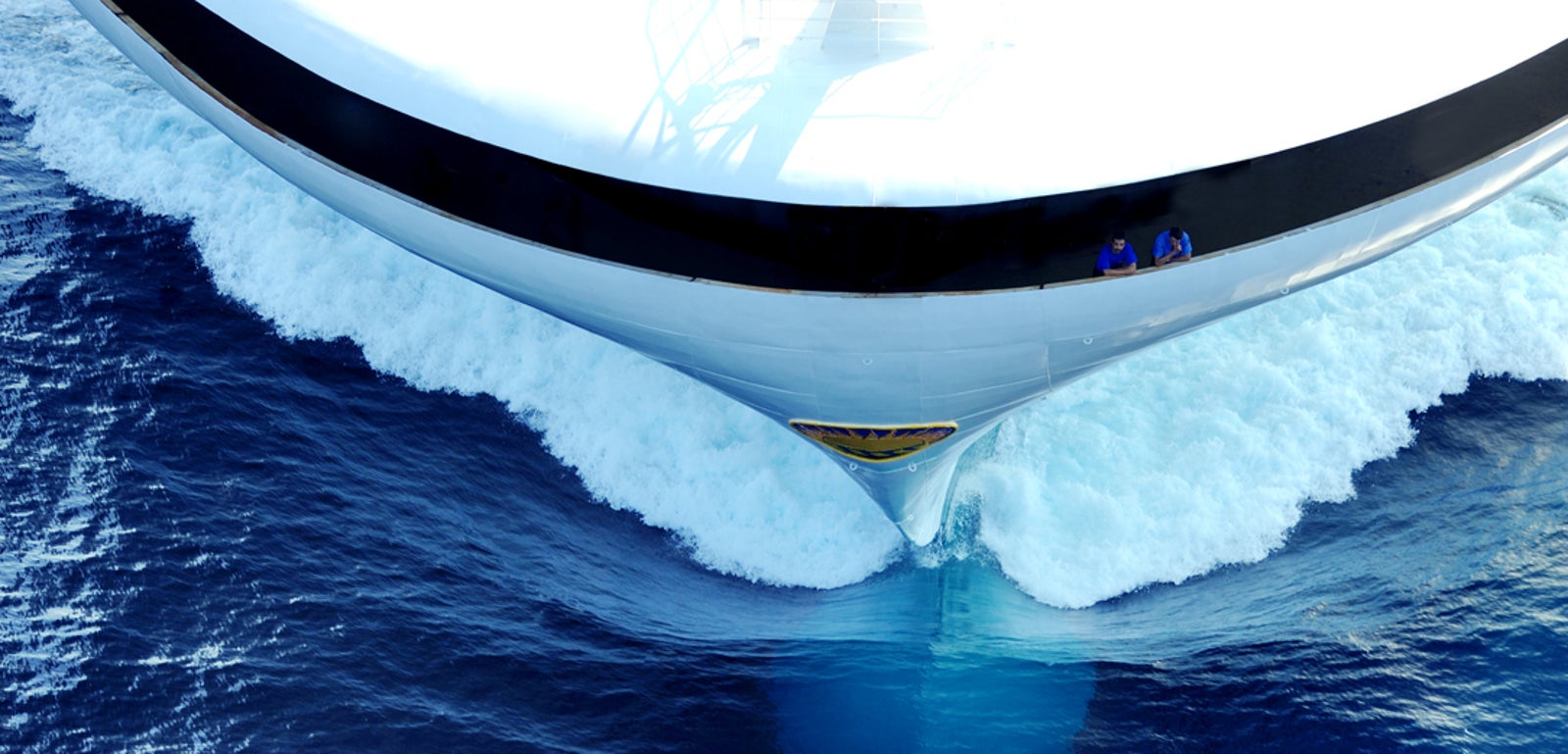 Fincantieri | Gruppo - Business - Prodotti - Navi da Crociera - Ruby Princess: Vista frontale di uno yacht di lusso elegante che taglia le onde blu vibranti dell’oceano, acqua schiumosa attorno alla prua, movimento ed eleganza evidenziati, logo visibile sul design della nave.