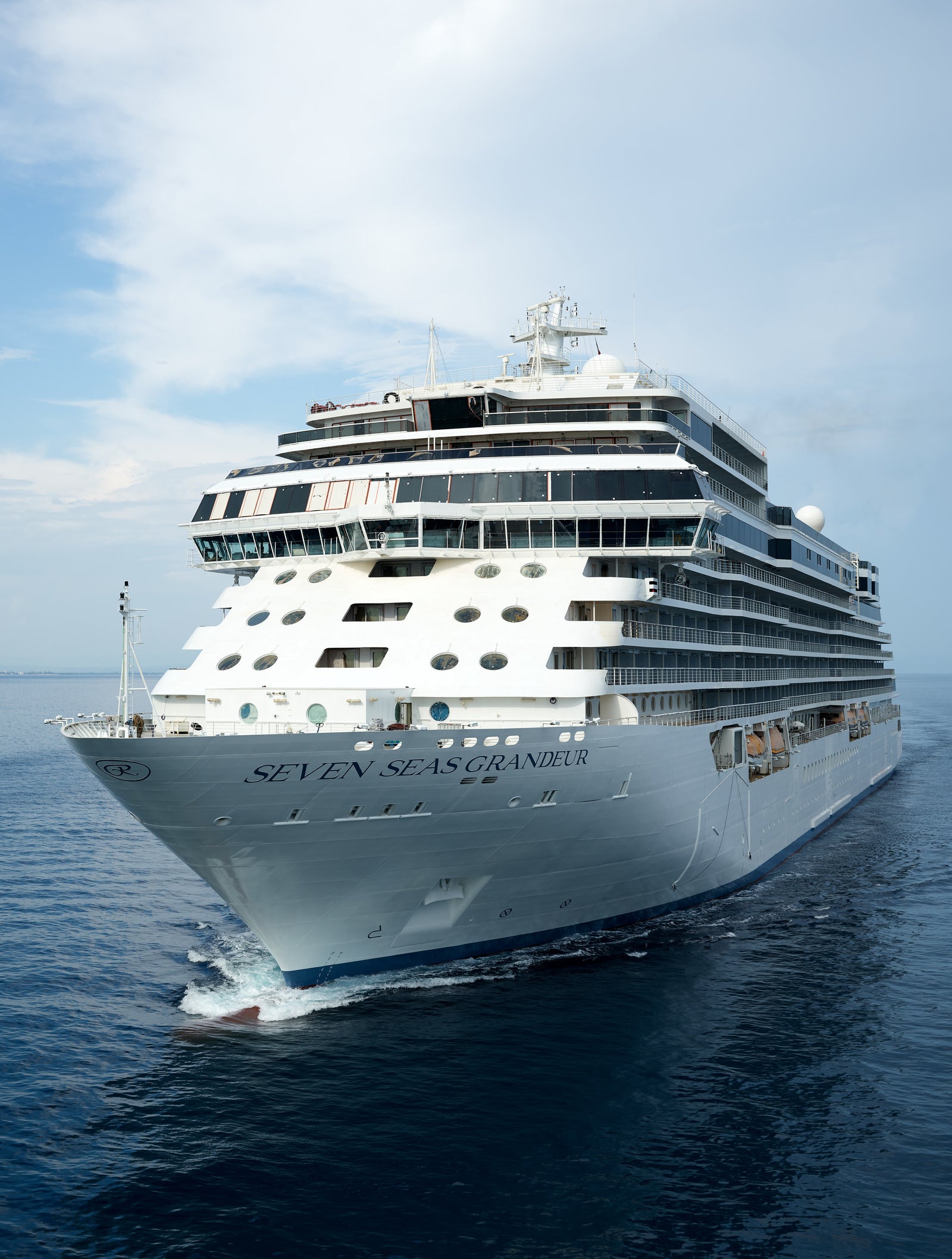 Fincantieri | Group - Business - Products - Cruise Ships - Seven Seas Splendor: Large operational luxury cruise ship with multiple decks, visible lifeboats and elegant design details, sailing on calm waters under partly cloudy sky.